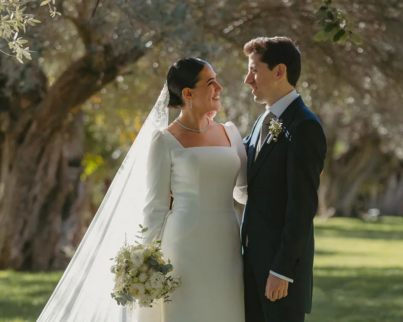 Pareja de novios mirándose en el jardín de olivos de la finca
