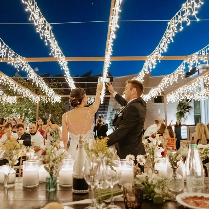 Novios brindando en el banquete decorado con velas y luces