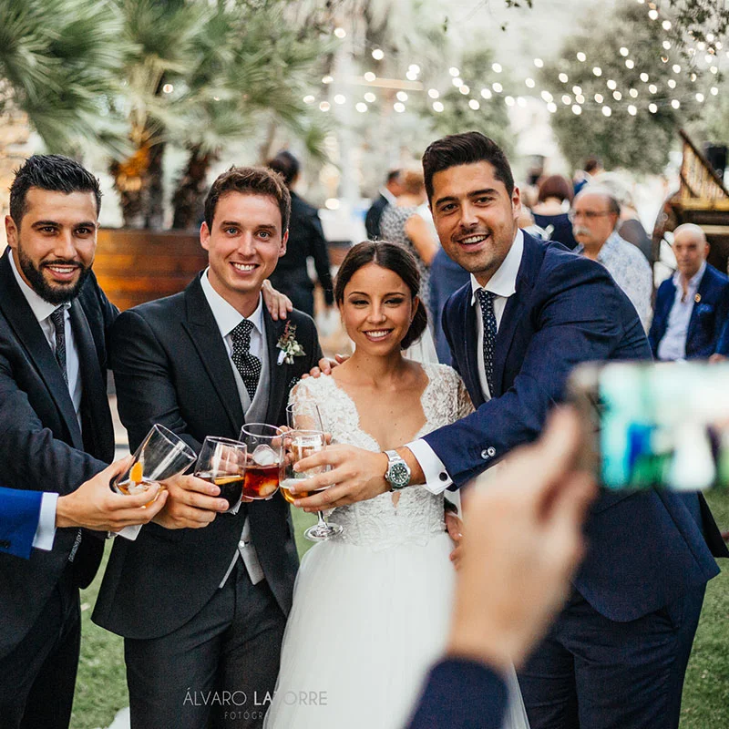 Novios e invitados brindando durante el cóctel en el jardín