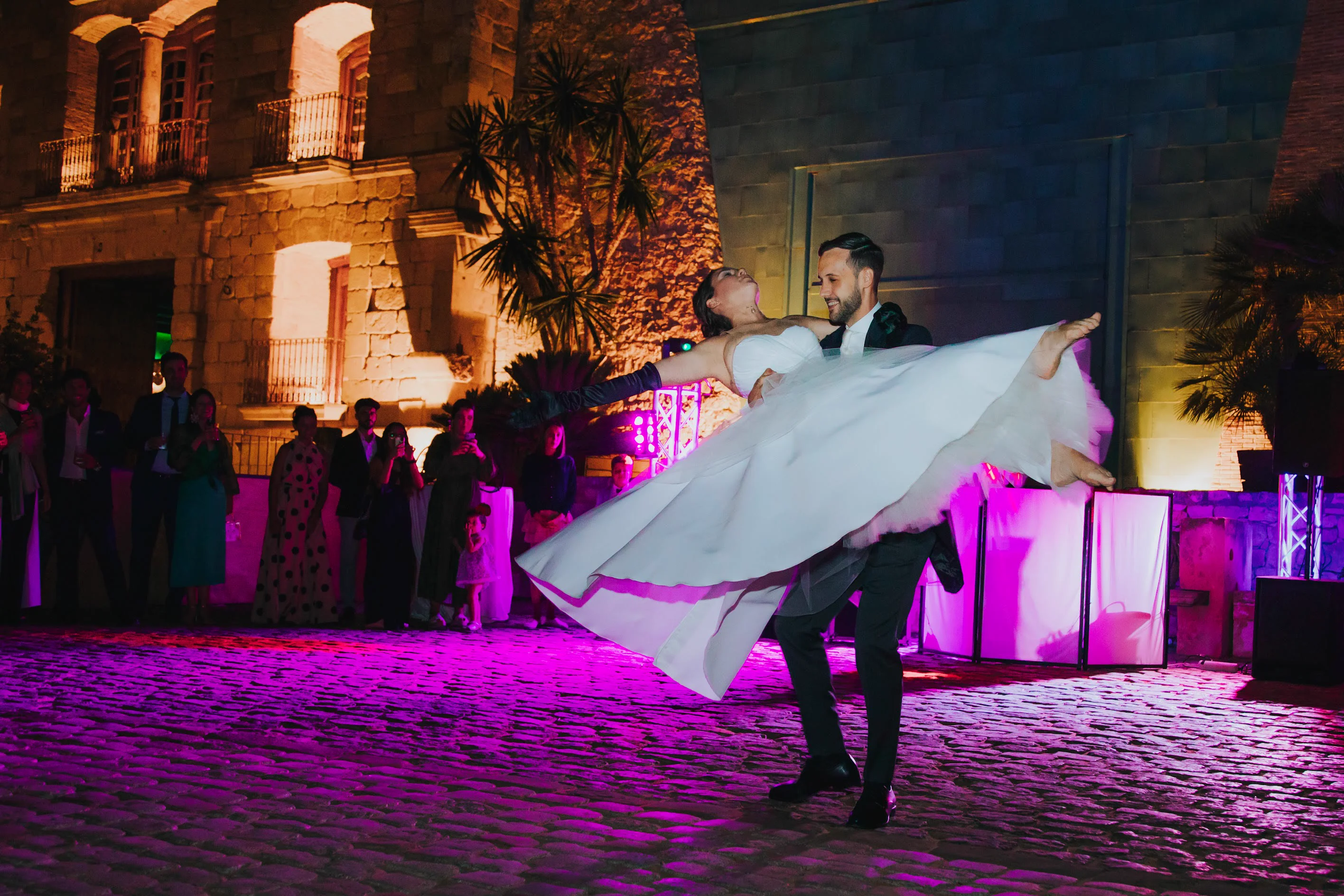 Novio levantando a la novia durante el baile nupcial nocturno